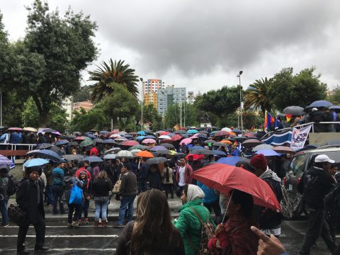Menschen auf Platz versammelt, mit Regenschrirmen